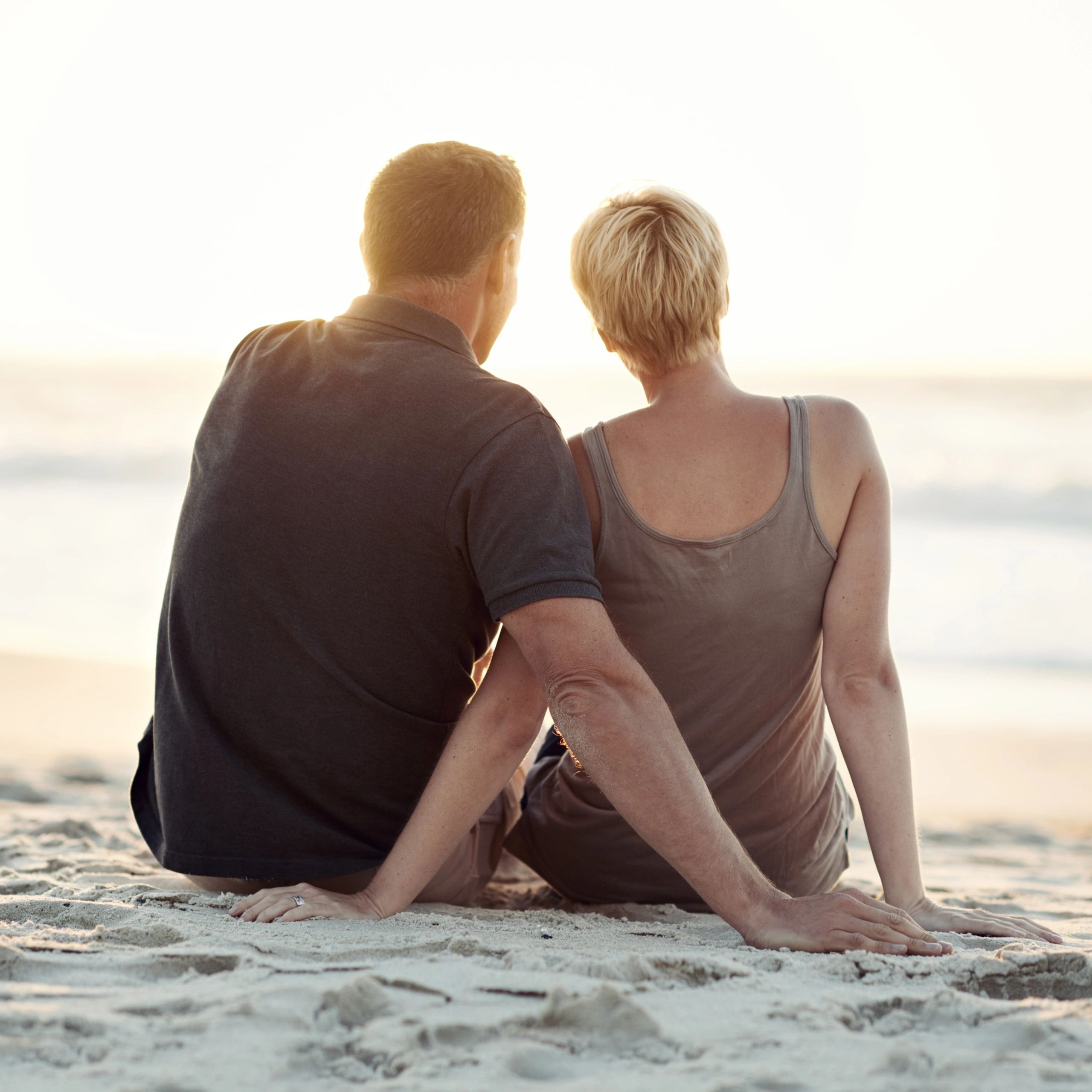 Couple sitting on the beach at sunset